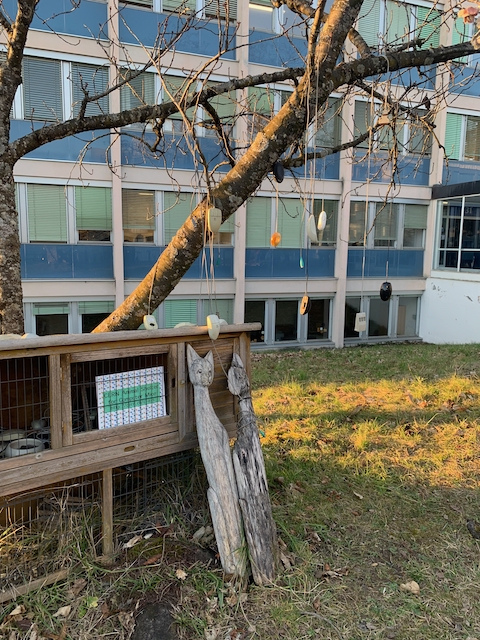 Devant un bâtiment des années cinquante, une cage contient des souris (informatiques), d'autres sont suspendues à un arbre
